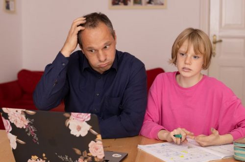 A father and daughter working on a laptop, focusing on home education activities.